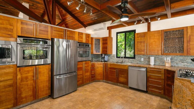 Kitchen corner with wood cabinets, stainless steel double ovens, a French-door refrigerator, a dishwasher and a window over the sink.